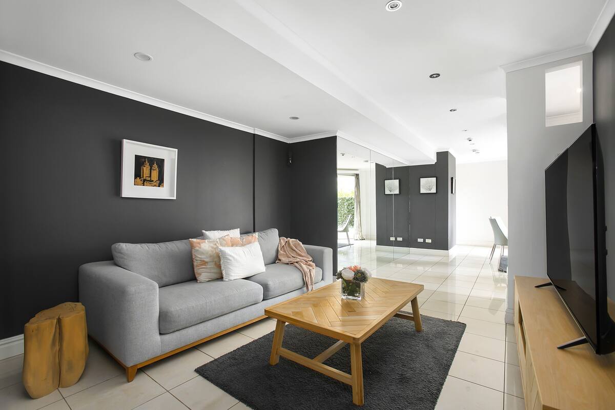 A modern living room with a grey sofa, a wooden coffee table, and a flat-screen TV.