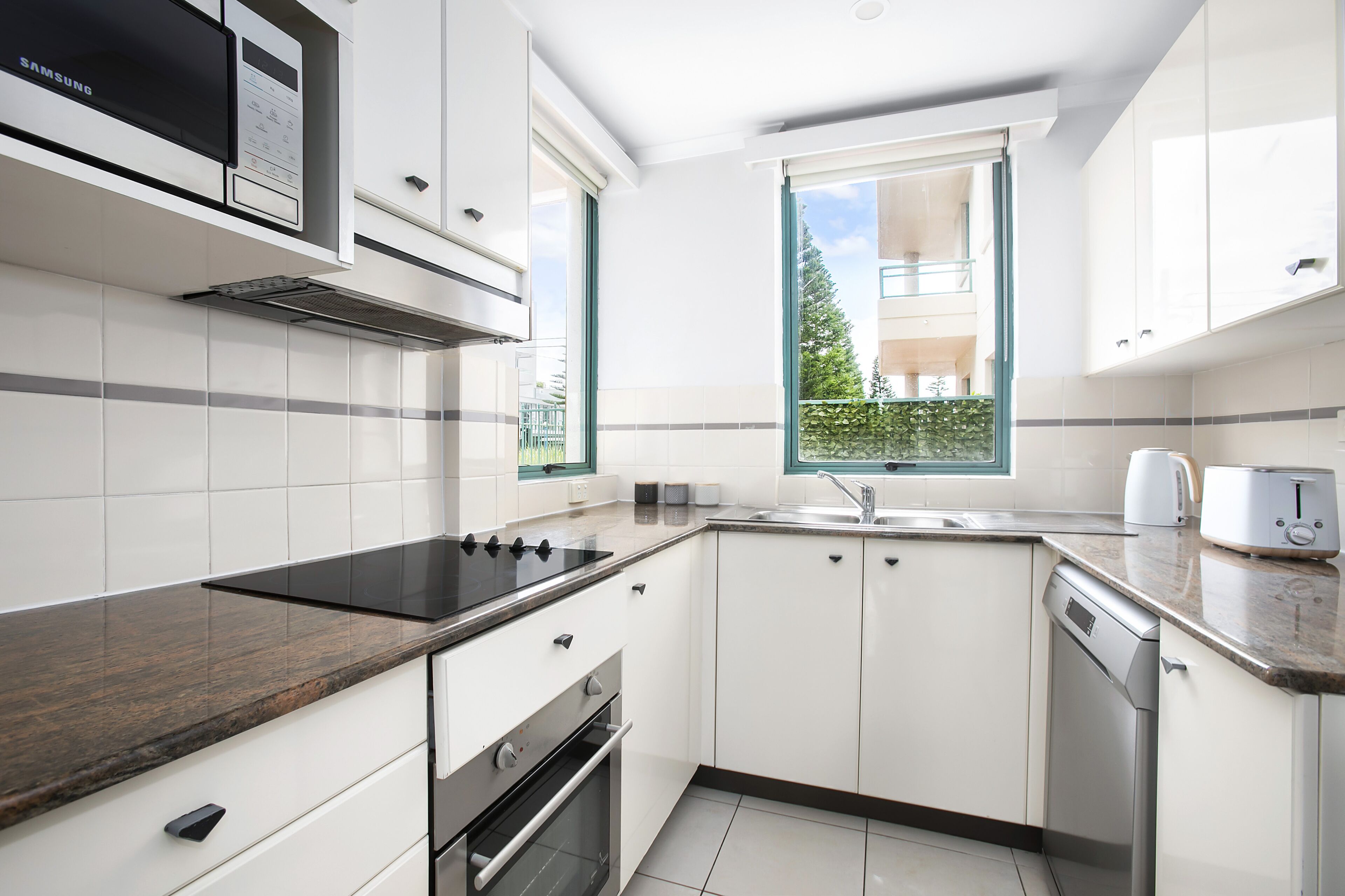 A modern kitchen with white cabinets, a built-in microwave, a stove, and a dishwasher.