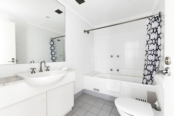A modern bathroom with a large sink, a bathtub, and a toilet. - AEA The Coogee View Serviced Apartments (Coogee)