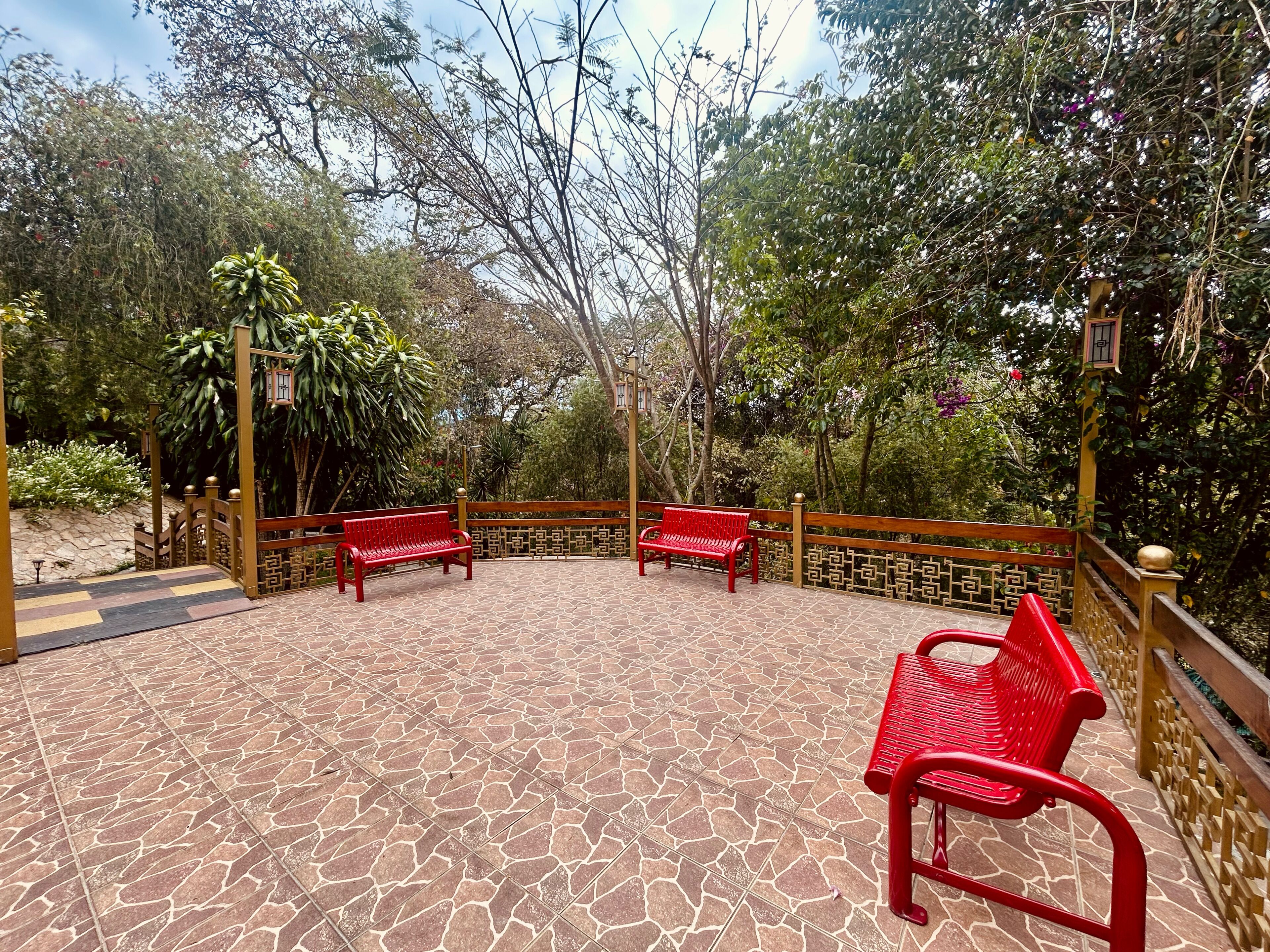 Un patio con suelo de baldosas, dos bancos rojos y una valla de madera.