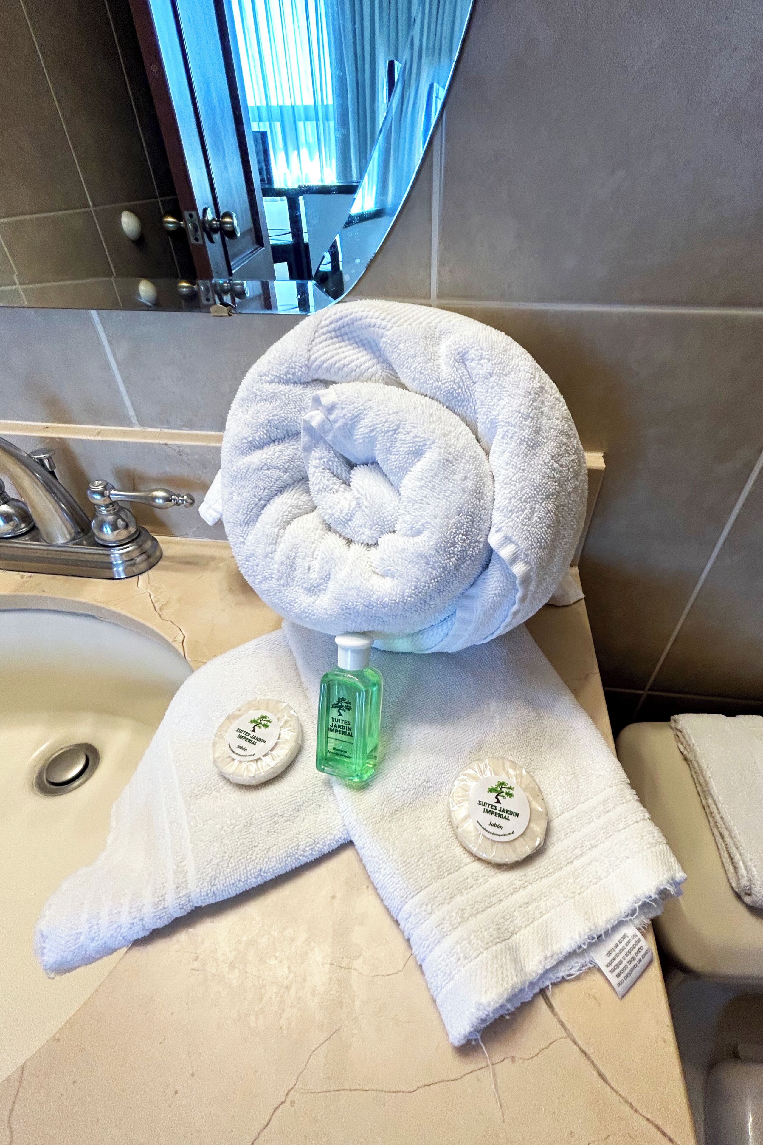 A bathroom with a sink, a mirror, and a towel rack with a folded towel.