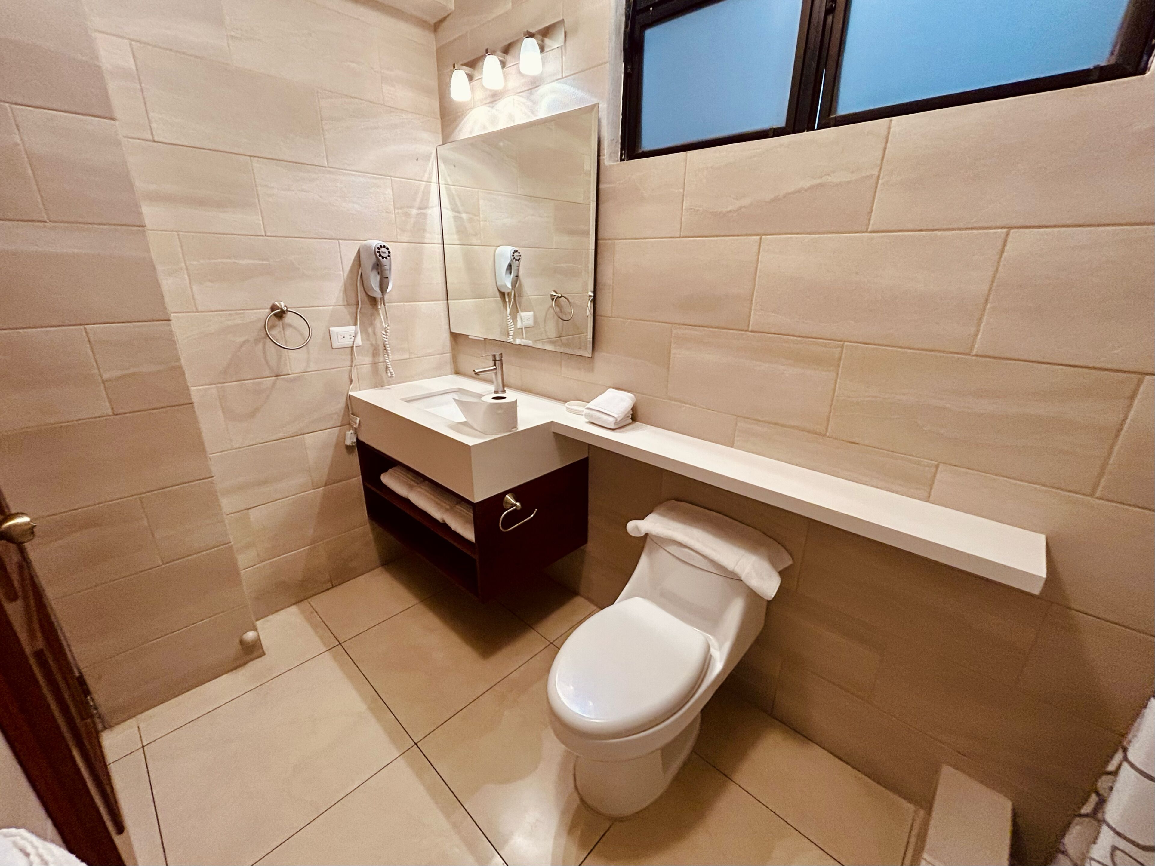 Een moderne badkamer met toilet, wastafel en spiegel.