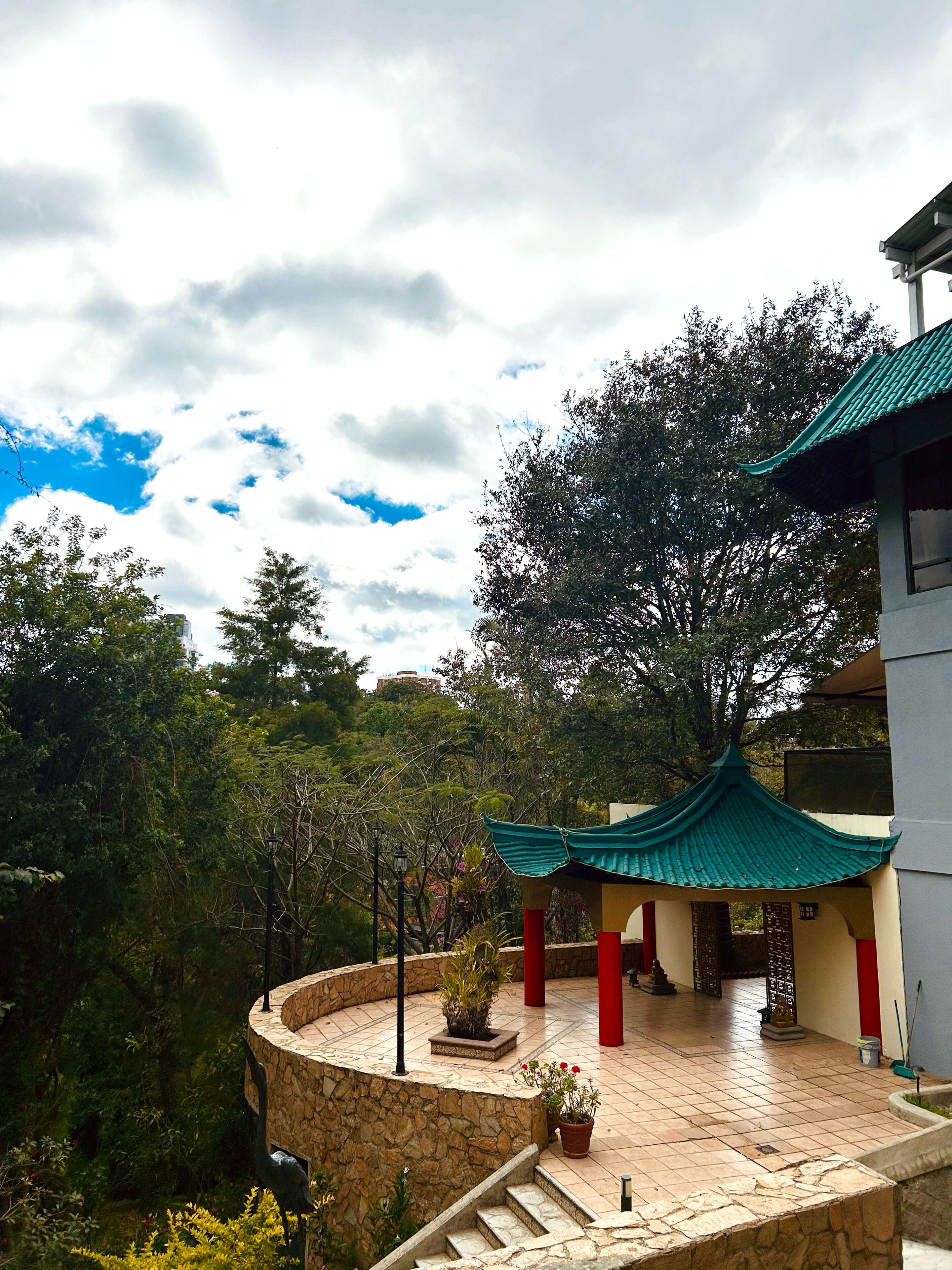 A traditional building with a curved stone pathway, a tiled courtyard, and a green-roofed pavilion.