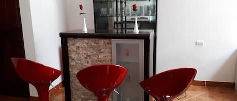 A modern bar area with a glass display case and two red bar stools.