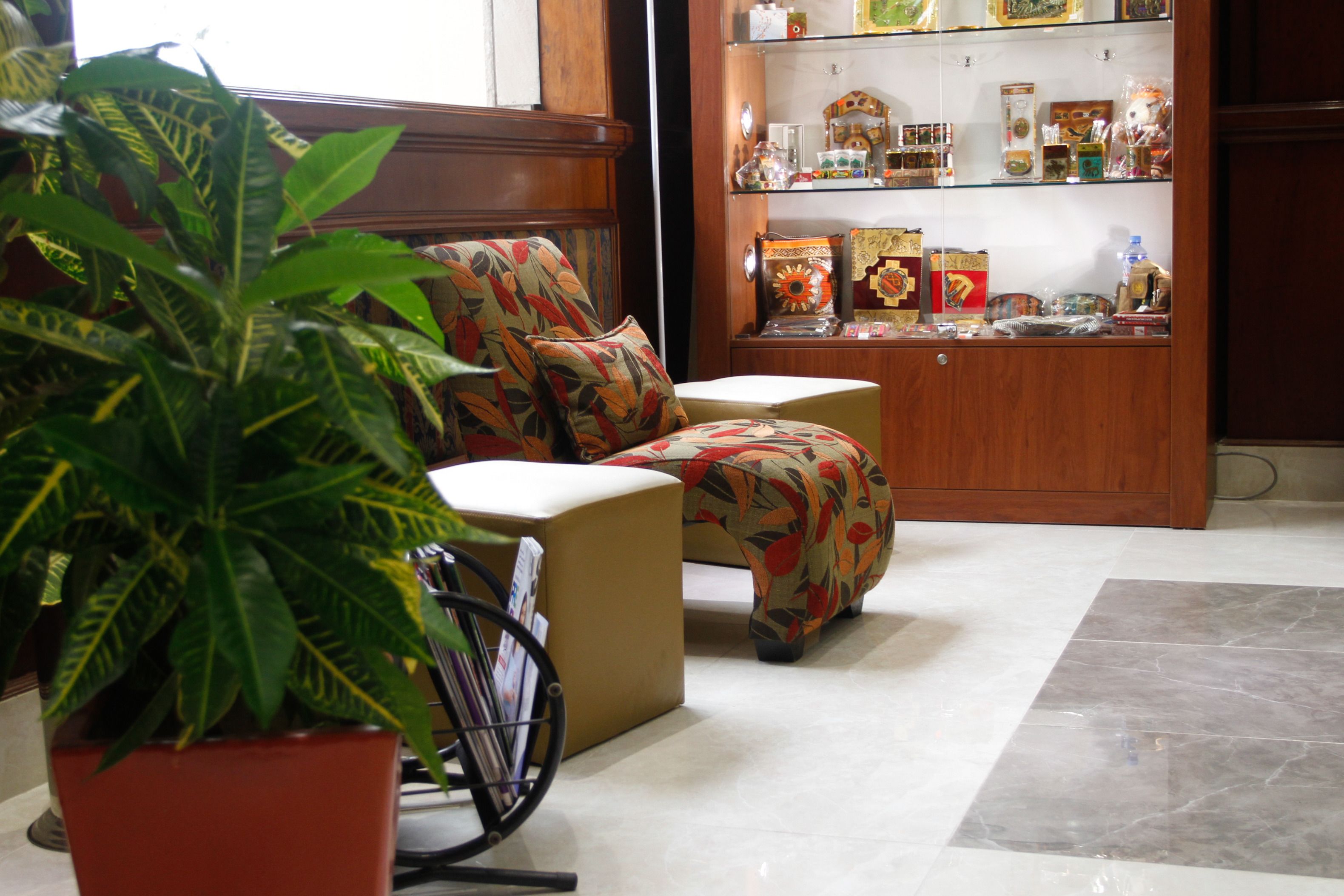 Una habitación con sofá, una mesita, una planta en maceta y un mueble con adornos.