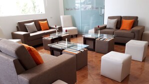 A modern living room with sofas, ottomans, and a glass coffee table. - Hotel Las Palmas (Lima)