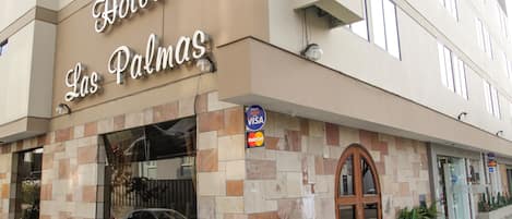 Hotel Las Palmas with a stone facade, a large arched entrance, and a Visa and MasterCard sign.