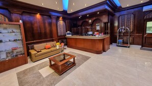 A lobby with a reception desk, a sofa, a coffee table, and a display of items on shelves. - Hotel Las Palmas (Lima)