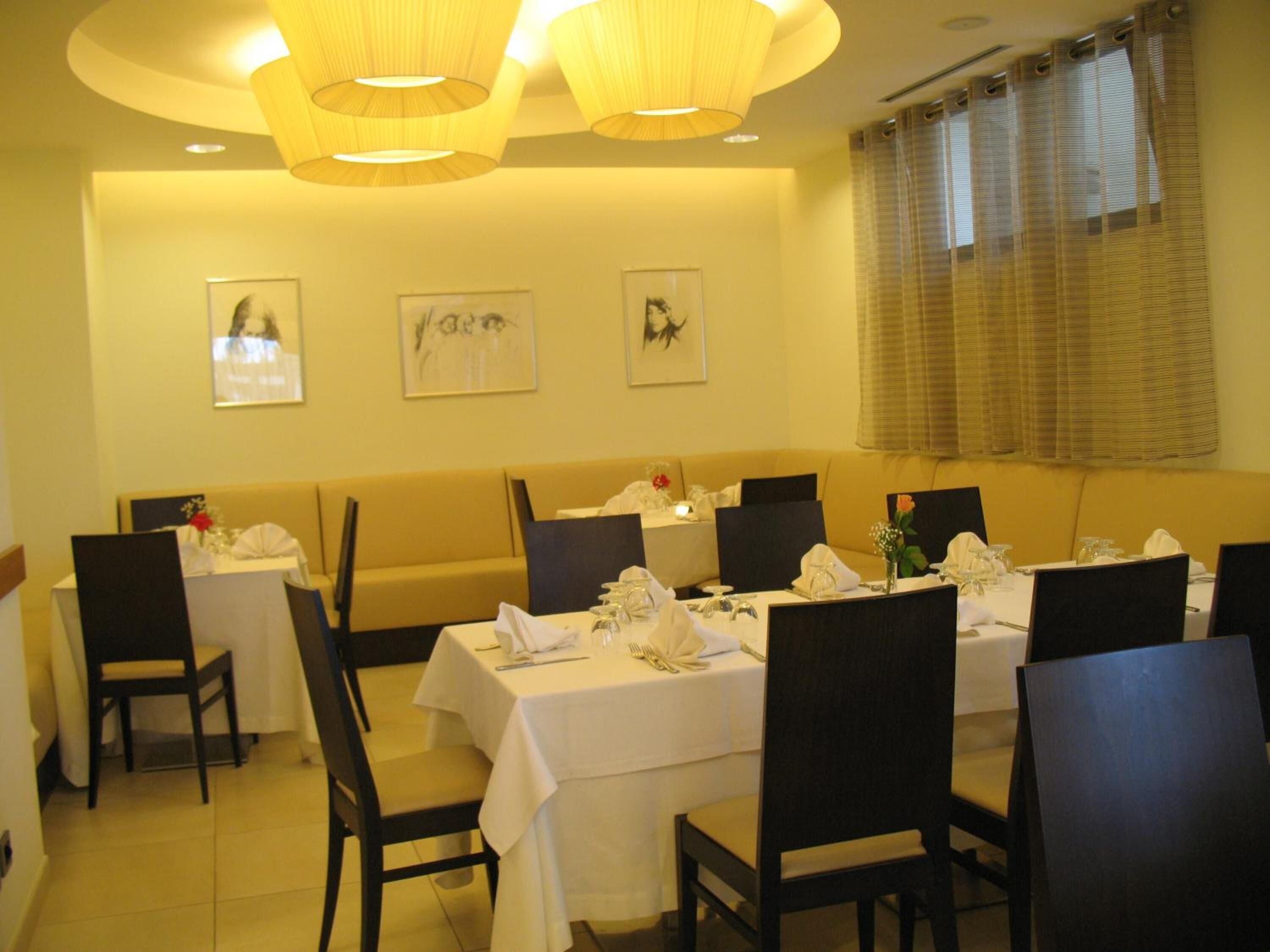 Un restaurante con mesas dispuestas para comer, sillas y un sofá.
