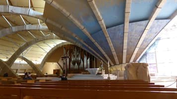 A church interior with arched ceilings, pews, and a large pipe organ.