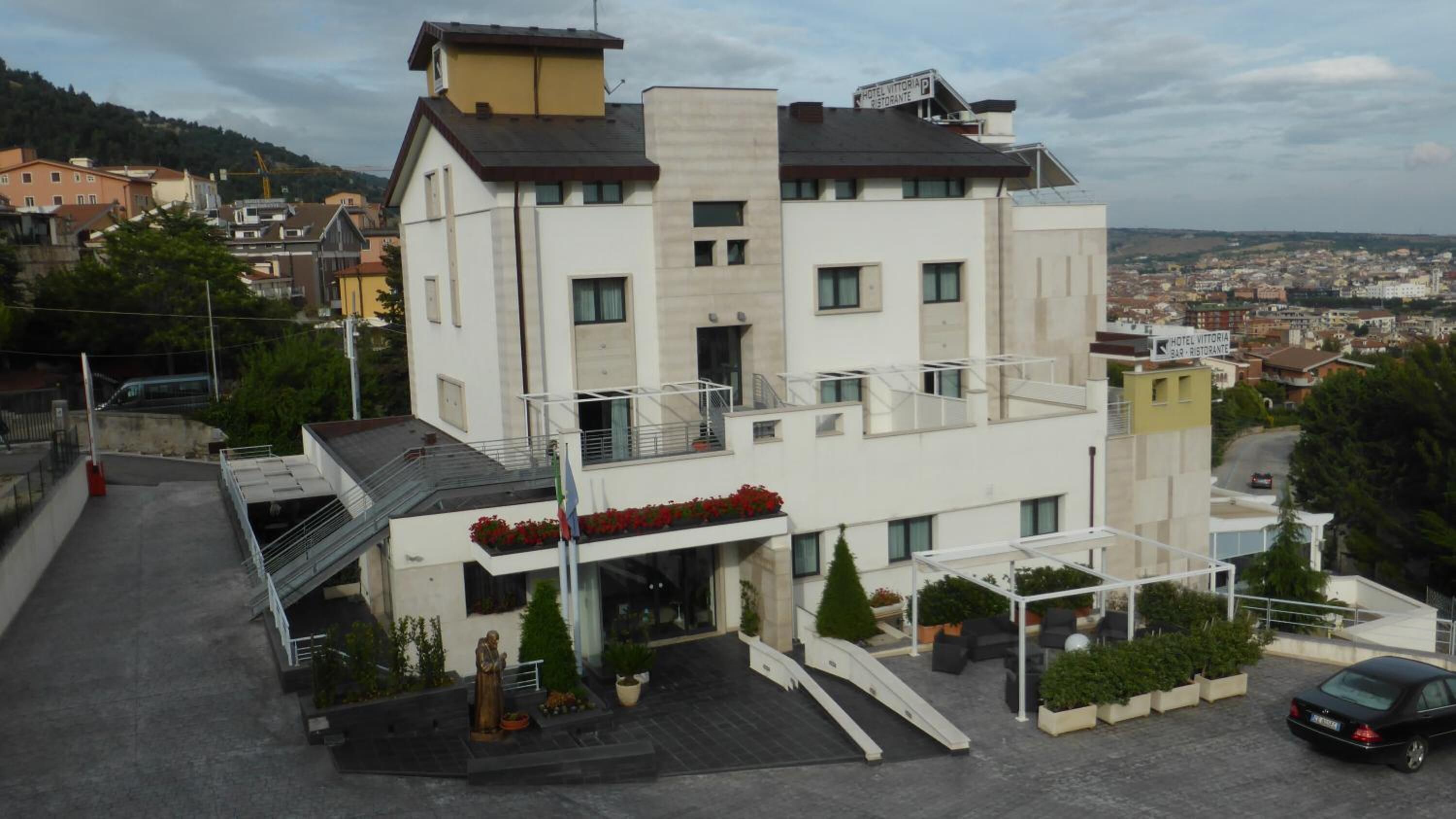 Un hotel moderno con techo plano, varios balcones y vistas a la ciudad.
