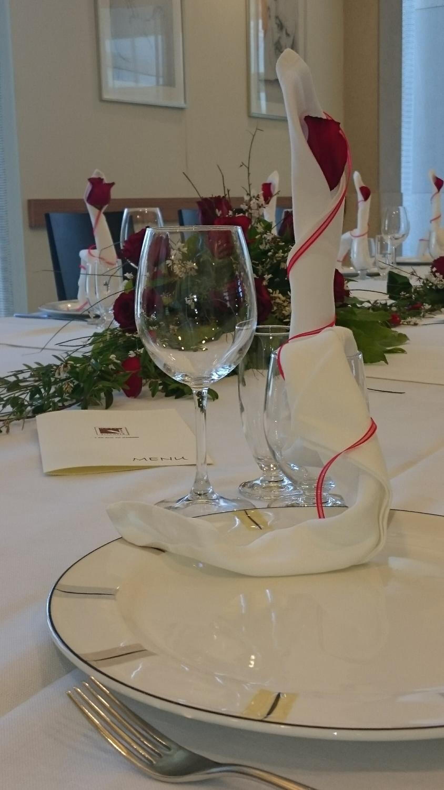 A table set for a formal dinner with a menu, wine glass, and folded napkin.