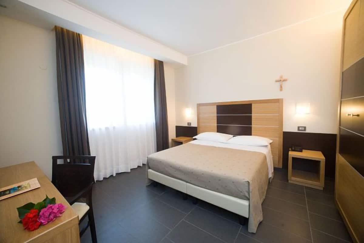 Una habitación de hotel con cama, mesitas de noche, escritorio y silla.