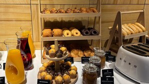 A breakfast buffet with pastries, donuts, and juice.