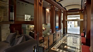 A lobby with a reception desk, a sofa, a patterned floor, and a view of the street outside.