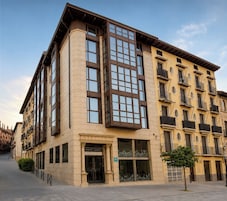 Un edificio de varios pisos con una entrada destacada, ventanas grandes y balcones.
