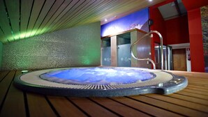 A hot tub with a mountain view backdrop, wooden flooring, and a red wall.