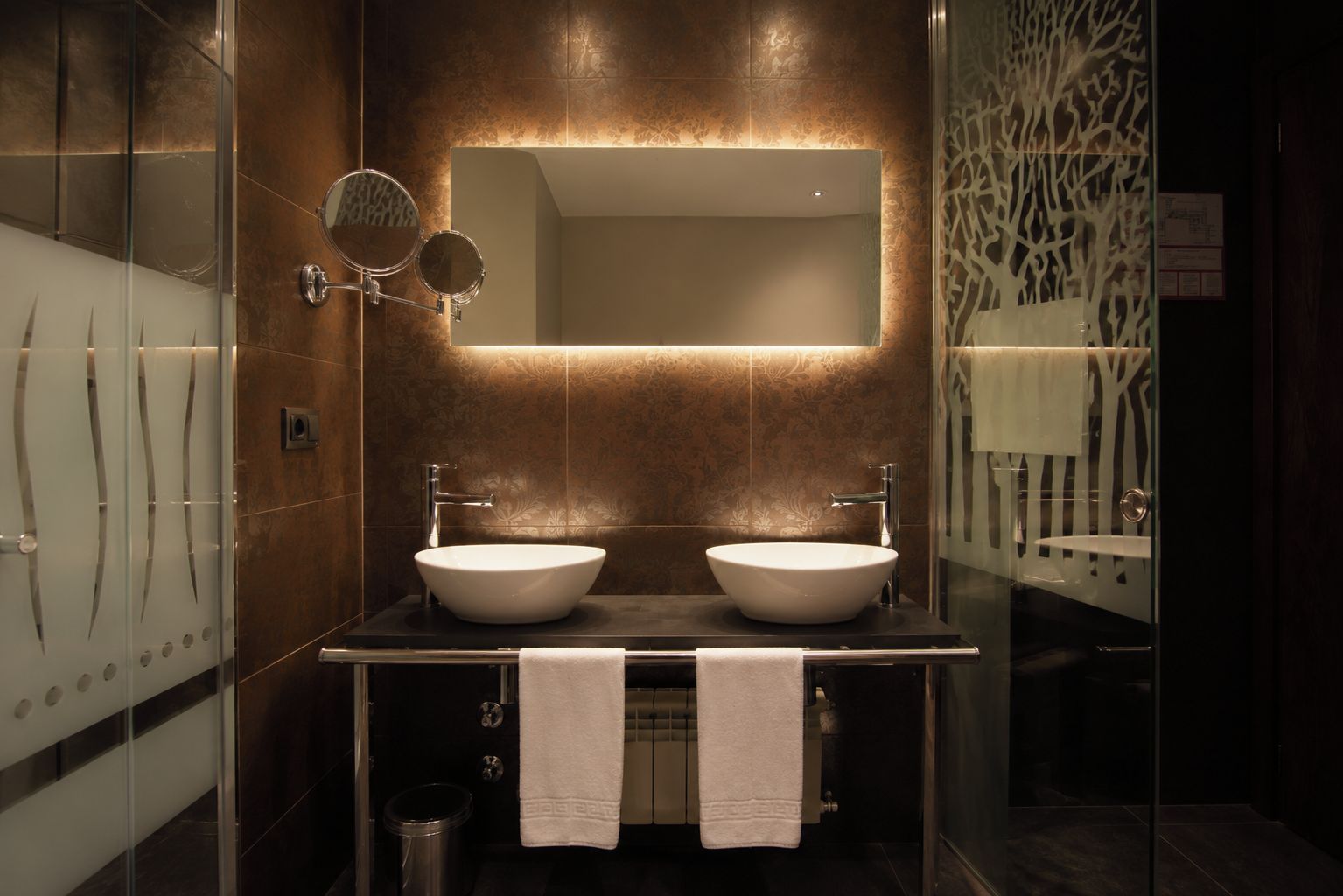 A modern bathroom with two sinks, a large mirror, and a decorative wall panel.