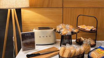 A table with a toaster, a bread basket, a bread tray, a knife, a cutting board, and a sign about gluten-free products.