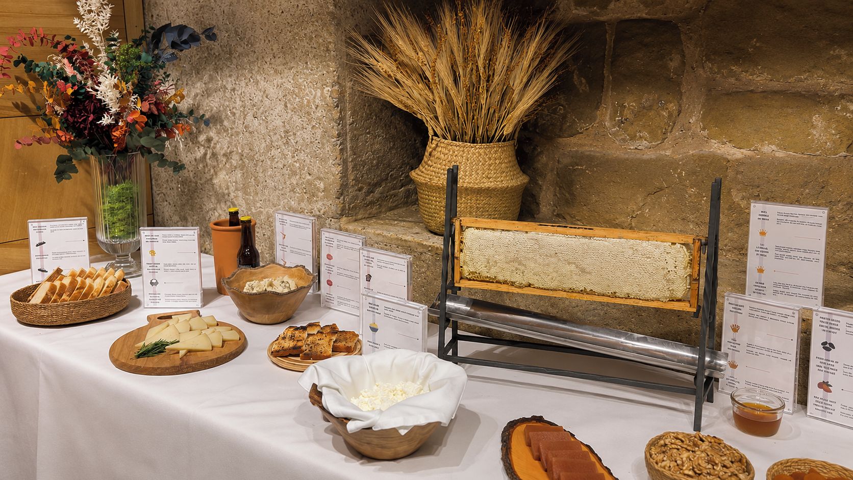 Una mesa de buffet con diversos alimentos, incluyendo queso, pan y un cortador de pan.