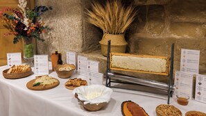 A buffet table with various food items, including cheese, bread, and a bread slicer.