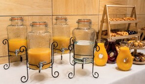 A breakfast buffet with multiple juice dispensers and a variety of pastries.
