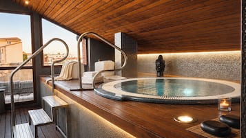 Un'area benessere con vasca idromassaggio, terrazza in legno e statua di Buddha.