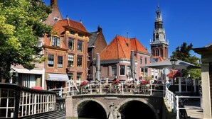 A canal-side bridge with buildings and a tower in the background. - Hotel Stad en Land (Alkmaar)