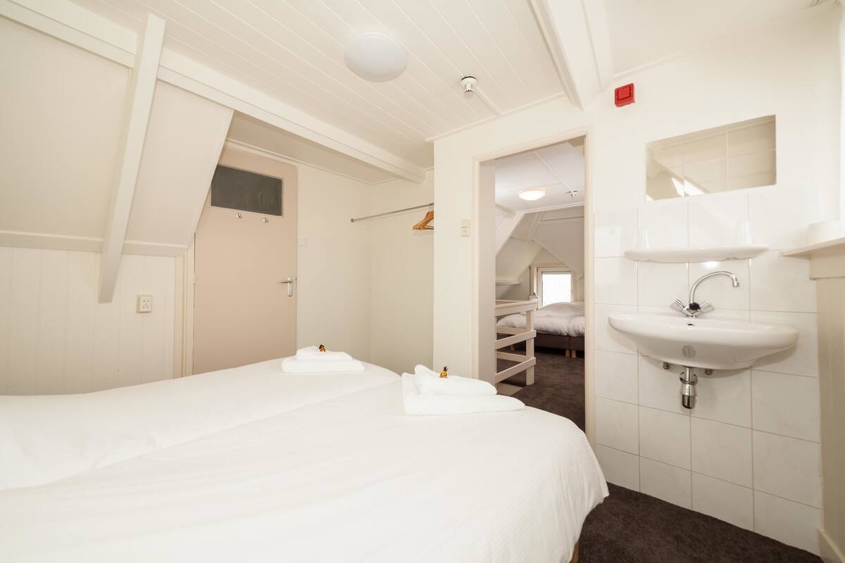 A hotel room with a large bed, a white sink, and a mirror above it.