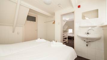 A hotel room with a large bed, a white sink, and a mirror above it.
