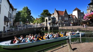 A narrow canal with a rowboat filled with people, surrounded by historic buildings and a bridge. - Hotel Stad en Land (Alkmaar)