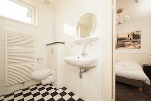 Bathroom features a toilet, sink, and shower area, with a wall-mounted picture adding a personal touch.