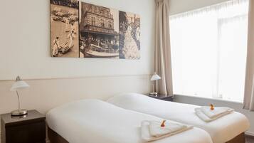 A hotel room with two beds, a nightstand, a lamp, and a large wall painting.