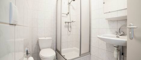 A modern bathroom with a toilet, shower, and sink.