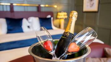 A bottle of Castelnau champagne in a metal bucket with two glasses, one with a strawberry.