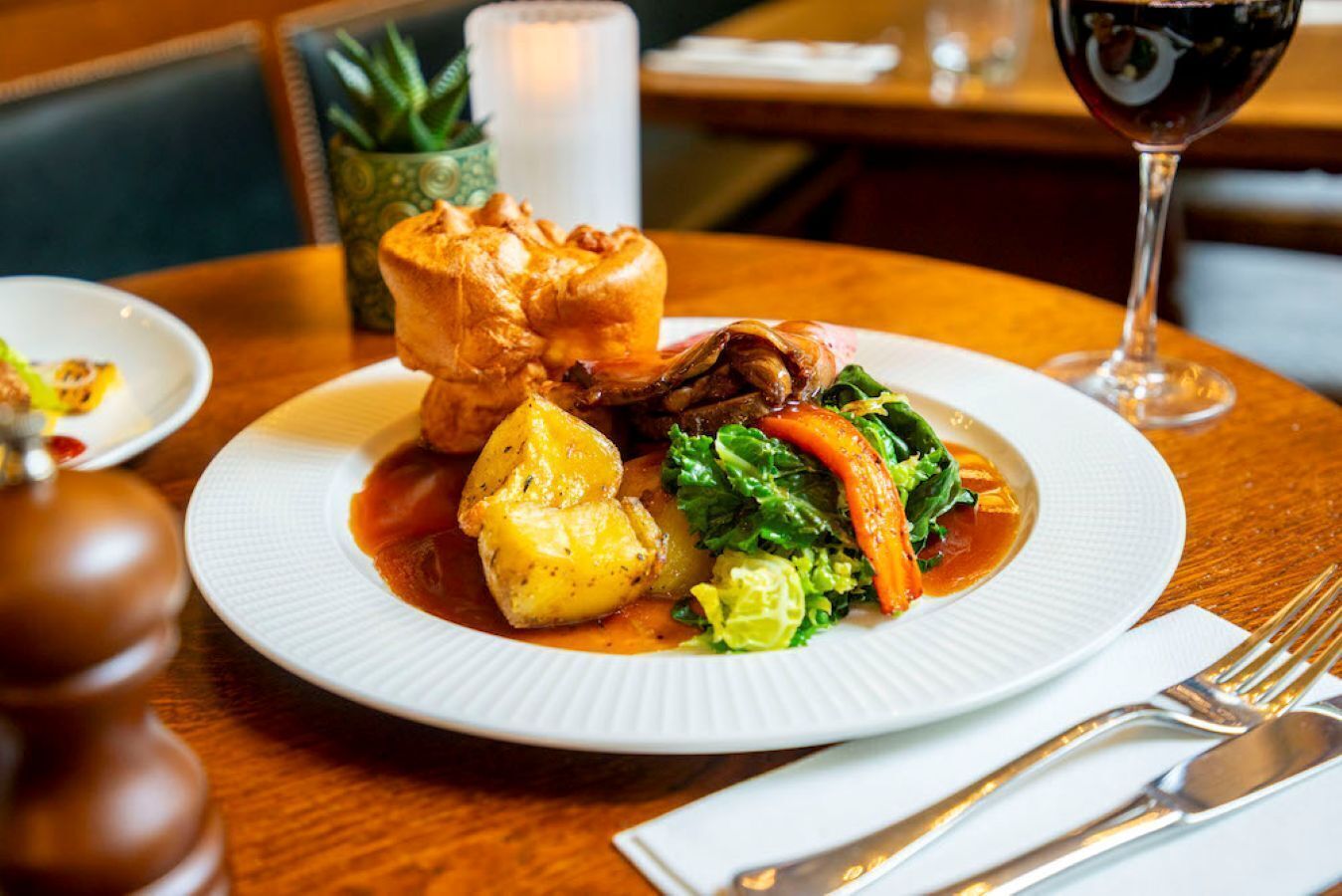 A plate of food with a glass of red wine on a wooden table.