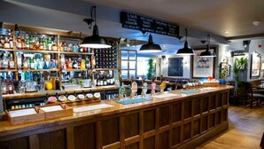 A bar area with a wooden counter, multiple bottles, and a menu board. - The Globe, Warwick, Warwickshire - Brunning & Price (Warwick)