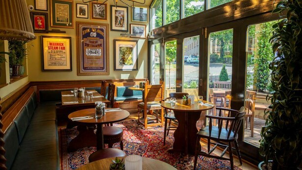 A restaurant with wooden furniture, large windows, and framed pictures on the walls. - The Globe, Warwick, Warwickshire - Brunning & Price (Warwick)