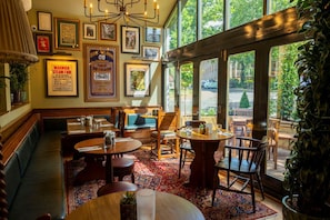 Un restaurant avec des meubles en bois, de grandes fenêtres et des tableaux encadrés accrochés aux murs.
