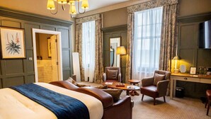 A hotel room with a large bed, two armchairs, a desk, a mirror, and a chandelier. - The Globe, Warwick, Warwickshire - Brunning & Price (Warwick)