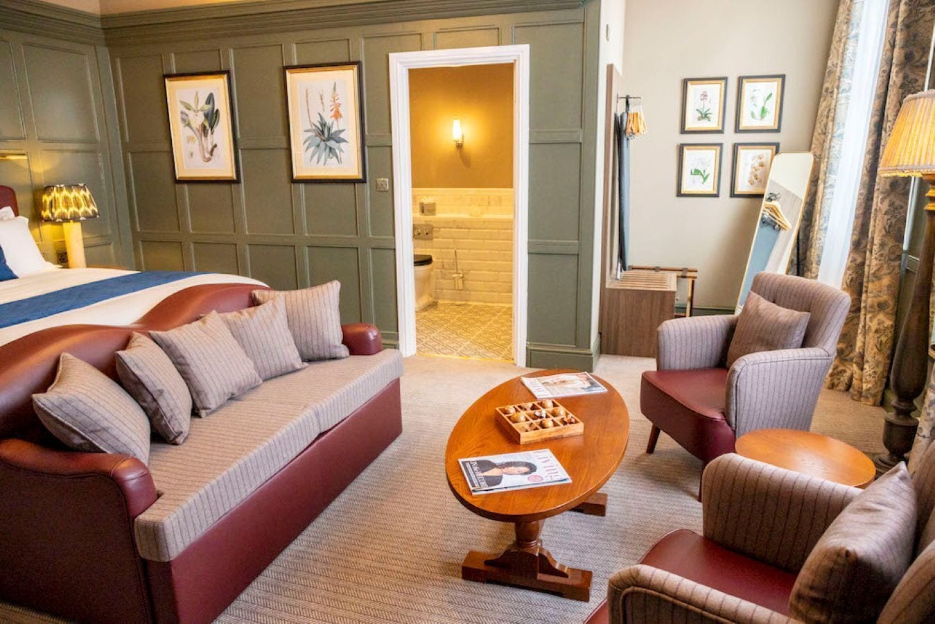 Une chambre d’hôtel comprenant un lit, un canapé, une chaise, une table basse et des œuvres d’art encadrées accrochées aux murs.