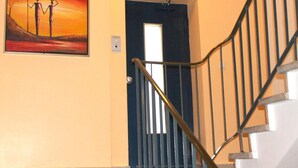 A staircase with a handrail and a door with a window. - Hotel Famosa (Düsseldorf)