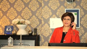 A reception desk with a clock, a framed certificate, and a vase with flowers. - Hotel Famosa (Düsseldorf)