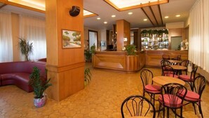 Vestíbulo de hotel con recepción, zona de estar y bar.