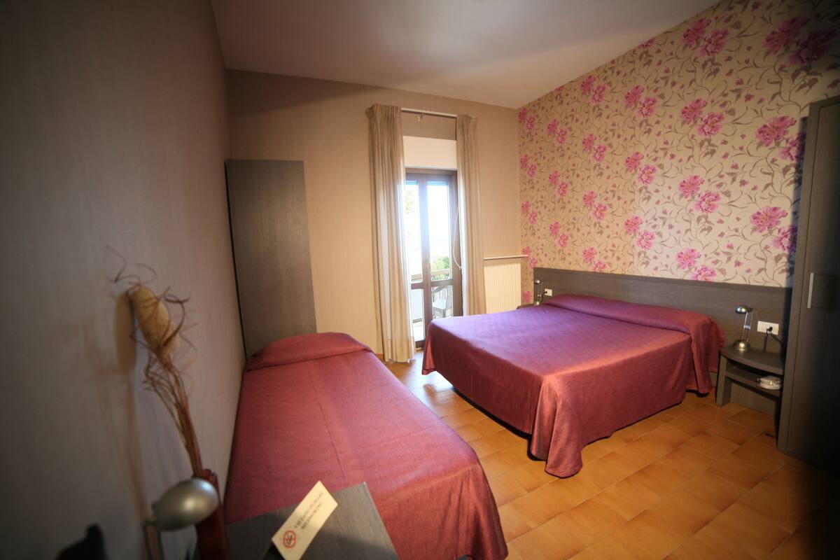 A room with two beds, a window, and a door.