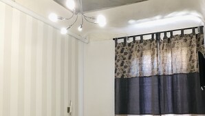 Habitación de hotel con cama, una silla y zona de ducha.