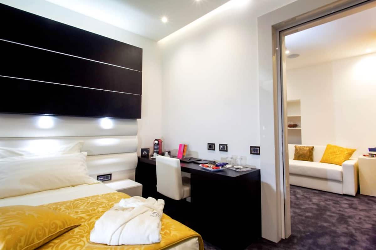 Una habitación de hotel con cama, escritorio, silla, sofá y espejo.