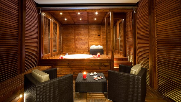 A spa room with wooden walls, a hot tub, and wicker furniture. - Style Hotel (Milan)