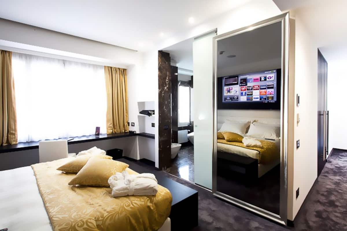 Una habitación de hotel con cama, escritorio, televisión y baño.