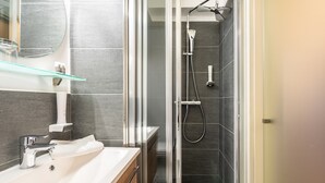 A modern bathroom with a glass-enclosed shower, a white sink, and a mirror above it.